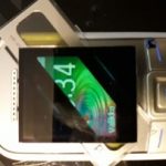 Ylhäältä päin kuvattu kännykkä, jonka näytön päällä kolme polarisaattoria joiden leikkauksen läpi näkee näytön värit