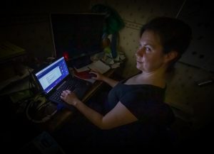 Martta istuu työpöydän ääressä läppärillä, huone pimeä lukuunottamatta tietokoneen näyttöä