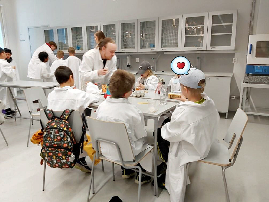 lapsia työskentelemässä kemianluokassa laboratoriotakeissa